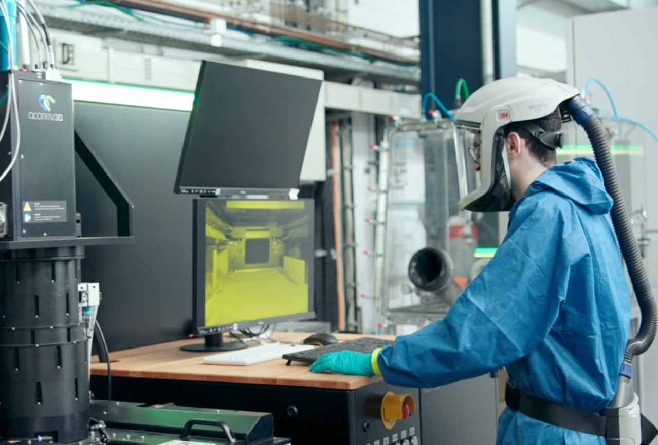 Mann in Schutzkleidung steht vor einer Maschine im Laser Zentrum. Titelbild eines Produktfilms Hannover von 52° Film für INLEAP Photonics.